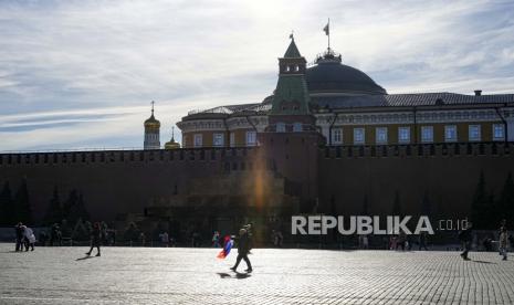 Seorang pria dengan bendera nasional Rusia berjalan di depan makam Lenin di Lapangan Merah pada hari yang cerah di Moskow, Rusia, Selasa, 11 Oktober 2022. Perekonomian Rusia terbukti kuat meski diterpa sanksi-sanksi Barat sejak tahun lalu.