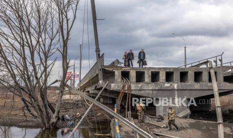  Orang-orang dengan tas mereka berdiri di jembatan yang hancur saat mereka melarikan diri dari kota garis depan Irpin, wilayah Kyiv (Kiev), Ukraina, 07 Maret 2022. Pemerintah Federasi Rusia pada Senin (7/3/2022) waktu setempat menyetujui daftar negara dan wilayah asing yang melakukan tindakan tidak bersahabat terhadap Rusia, perusahaan, dan warganya.