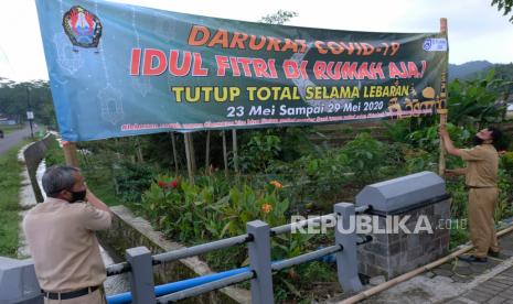 Perangkat desa memasang spanduk himbauan untuk di rumah saja saat hari raya Idul Fitri di Gunung Gempol, Jumo, Temanggung, Jawa Tengah, Selasa (19/5/2020). Pemerintah menghimbau umat Islam tidak malaksanakan takbir keliling, shalat Id di lapangan maupun di masjid dan saling berkunjung pada perayaan Idul Fitri tahun ini guna mencegah penyebaran COVID-19