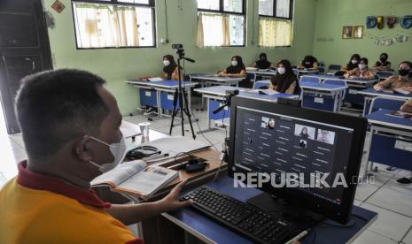 Seorang Guru (kiri) menerangkan materi pembelajaran kepada murid SMPN 2 Bekasi secara hybrid atau kombinasi antara tatap muka terbatas dengan pembelajaran secara daring di Bekasi, Jawa Barat. Disdik Kabupaten Bekasi berencana membuka PTM 100 persen saat bulan Ramadhan.