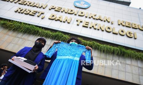 Dua mahasiswa Universitas Negeri Yogyakarta (UNY) menggelar aksi unjuk rasa dengan membawa baju dansa di depan Gedung Kemendikbudristek, Jakarta, Jumat (10/2/2023). Dalam aksinya para mahasiswa menuntut Mendikbudristek Nadiem Makarim untuk menuntaskan polemik sistem Uang Kuliah Tunggal (UKT) yang dianggap sebagai bentuk komersialisasi pendidikan akibat mahalnya biaya kuliah di Indonesia.