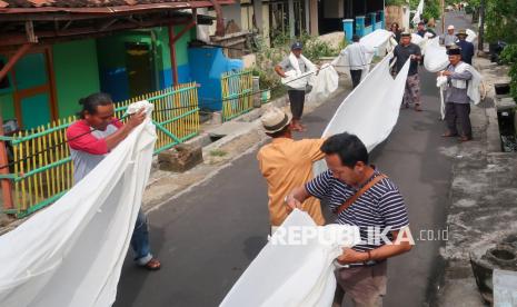 Warga suku Osing melipat kain kafan (lawon) usai dibersihkan di Balai Tajuk Cungking, Banyuwangi, Jawa Timur, Kamis (13/2/2025). Tradisi resik lawon yang digelar secara turun-temurun oleh warga suku Osing itu setiap bulan Ruwah pada penanggalan Jawa untuk mensucikan diri jelang menghadapi bulan suci Ramadhan. 