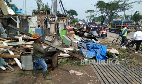 Warga bersama petugas dari unsur terkait berupaya membereskan bangunan dan pohon-pohon tumbang akibat angin puting beliung yang terjadi di Jalan Rancaekek, Kabupaten Bandung, Kamis (22/2/2024). Menurut Pakar klimatologi di Badan Riset dan Inovasi Nasional (BRIN), mengatakan, angin kencang yang merusak banyak bangunan di Rancaekek  diduga jenis badai tornado. 