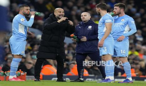 Pelatih Manchester City Josep Guardiola memberikan instruksi ke pasukannya saat dikandaskan Tottenham, Ahad (20/2/2022).