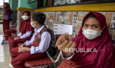 Pelajar menunjukkan tanda suhu tubuh sebelum memasuki area sekolah untuk mengikuti pembelajaran tatap muka terbatas (PTMT) di SDN 084 Cikadut, Jalan Jamaras, Kota Bandung, Jumat (12/11). Pemerintah Kota Bandung melalui Dinas Pendidikan Kota Bandung menyatakan, PTMT di 54 sekolah yang sempat ditutup sementara akibat persentase kasus Covid-19 diatas angka lima persen dari hasil tes acak PCR akan digelar kembali. Hal itu mengingat kondisi mayoritas pelajar dan guru yang telah sembuh serta proses 3T (tracing, testing dan treatment) yang hampir selesai. Foto: Republika/Abdan Syakura