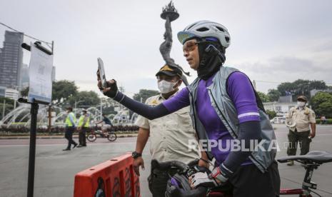 Warga memindai kode batang saat berolahraga pada Hari Bebas Kendaraan Bermotor (HBKB) atau Car Free Day (CFD) di kawasan Jalan Jenderal Sudirman, Jakarta, Ahad (22/5/2022). Pemprov DKI Jakarta kembali menggelar HBKB di enam titik dengan pola terbatas mulai Minggu 22 Mei 2022 yang berlangsung pukul 06.00-10.00 WIB. 