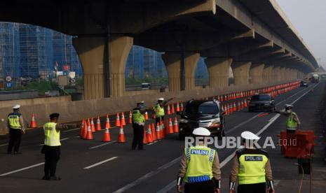 Petugas gabungan mengarahkan kendaraan untuk keluar Tol Cikarang Barat, di ruas Tol Cikampek, Jabar,Ahad (26/042020). Larangan mudik dan sosialisasi aturan Pembatasan Sosial Berskala Besar (PSBB) di ruas tol itu guna mencegah penyebaran COVID-19 dengan membatasi kendaraan pribadi dan angkutan umum yang melintas