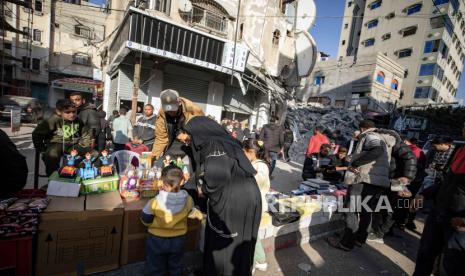 Warga Palestina berjalan melewati kios-kios yang didirikan di jalan pada hari pertama Ramadhan, di Rafah, Jalur Gaza selatan, 11 Maret 2024. 