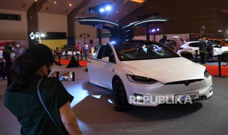 Pengunjung memotret mobil listrik Tesla Model X yang dipamerkan dalam IIMS Hybrid 2021 di JiExpo Kemayoran, Jakarta, Ahad (18/4/2021). Sebuah laporan teknis menunjukkan kendaraan itu tidak dapat mengenali rintangan seperti penyempitan lokasi konstruksi. 