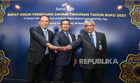 Dirut Bank BJB Yuddy Renaldi (kanan) berfoto bersama dengan Gubernur Jawa Barat Ridwan Kamil (tengah) usai Rapat Umum pemegang Saham Tahunan Tahun Buku 2021 PT Bank Pembangunan Daerah Jawa Barat dan Banten di The Trans Luxury Hotel, Kota Bandung, Rabu (30/3/2022). RUPST salah satunya memberikan persetujuan atas Laporan Tahunan Direksi termasuk pengesahan Laporan Keuangan Perseroan dan Laporan Pelaksanaan Tugas Pengawasan Dewan Komisaris untuk Tahun Buku 2021. Agenda lainnya adalah penetapan penggunaan laba bersih perseroan termasuk pembagian dividen untuk Tahun Buku 2021, yakni sebesar Rp1,042 Triliun atau sebesar Rp 99,11per lembar saham. Angka tersebut setara dengan 51,77% dari laba bersih yang berhasil dibukukan oleh bank bjb di Tahun Buku 2021.