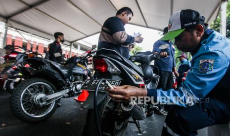 Petugas melakukan uji emisi kendaraan motor di kawasan Gelora Bung Karno, Jakarta, Rabu (27/9/2023). Dinas Lingkungan Hidup DKI Jakarta dan Ditlantas Polda Metro Jaya akan kembali melakukan razia dan tilang emisi kendaraan di tempat pada bulan Oktober. Selain itu, Pemprov DKI Jakarta juga akan menerapkan tarif disinsentif di 131 titik lokasi parkir bagi kendaraan yang tidak lulus uji emisi.