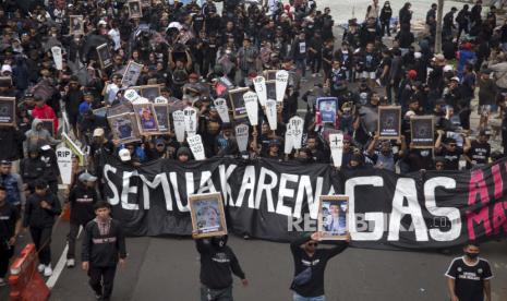 Ilustrasi spanduk bertuliskan 'INI SEMUA KARENA GAS AIR MATA' dan dan foto-foto para korban Tragedi Kanjuruhan.