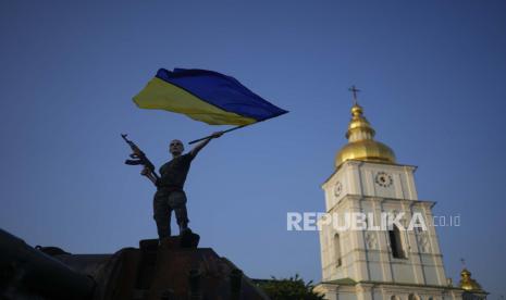 Seorang wanita mengibarkan bendera Ukraina di atas tank Rusia yang hancur di Kyiv, Ukraina, Jumat, 10 Juni 2022. Badan eksekutif Uni Eropa pada Jumat (17/6/2022) merekomendasikan agar Ukraina dan Moldova diberikan status kandidat untuk bergabung dengan blok 27 negara tersebut.