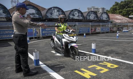 Personel Satlantas Polrestabes Bandung memberi arahan kepada peserta ujian praktik pembuatan surat izin mengemudi (SIM) C di Polrestabes Bandung, Kota Bandung, Jawa Barat, Selasa (8/8/2023). Satlantas Polrestabes Bandung mulai memberlakukan perubahan uji praktik pembuatan SIM C dengan meniadakan tes rute slalom atau zig-zag, mengganti rute angka delapan menjadi huruf S, lebar rute menjadi sekitar dua meter dan uji pengereman keseimbangan.