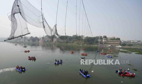 Tim penyelamat di kapal mencari di sungai Machchu di sebelah jembatan kabel yang runtuh pada hari Minggu di kota Morbi di negara bagian barat Gujarat, India, Selasa, 1 November 2022. Sebuah jembatan kabel gantung berusia seabad runtuh ke sungai Minggu malam, mengirim ratusan orang terjun ke air dalam salah satu kecelakaan terburuk di negara itu dalam beberapa tahun.