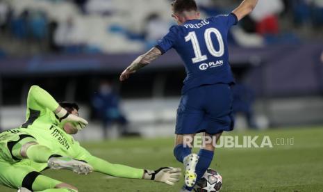 Gelandang Chelsea Christian Pulisic menghindari kiper Real Madrid Thibaut Courtois pada pertandingan leg pertama semifinal Liga Champions di stadion Alfredo di Stefano, Madrid, Spanyol, Selasa (27/4) Pertandingan tersebut berakhir dengan skor imbang 1-1, melalui tendangan Karim Benzema dari Real Madrid dan Christian Pulisic dari Chelsea. (AP Photo/Bernat Armangue)