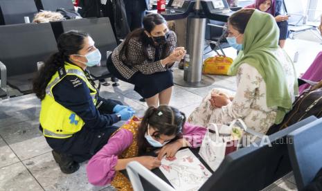 Menteri Dalam Negeri Inggris Priti Patel, tengah atas, berbicara dengan seorang pengungsi dari Afghanistan yang tiba dengan penerbangan evakuasi di Bandara Heathrow di London, Kamis 26 Agustus 2021. 