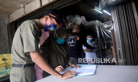 Petugas Satpol PP membuat berita acara saat melakukan pengawasan PSBB di salah satu tempat usaha di Kawasan Jatinegara, Jakarta, Selasa (15/9). Pengawasan tersebut dilakukan untuk memastikan masyarakat untuk mematuhi dan tertib aturan yang berlaku selama PSBB di DKI Jakarta.Prayogi/Republika. 