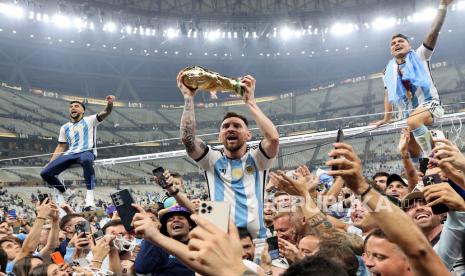 Lionel Messi dari Argentina (Tengah) mengangkat trofi saat ia merayakan dengan rekan satu tim dan penggemar memenangkan Final Piala Dunia FIFA 2022 antara Argentina dan Prancis di stadion Lusail, Lusail, Qatar, 18 Desember 2022. Messi dan rekan-rekannya akan menyambangi Indonesia untuk menghadapi Timnas pada bulan Juni mendatang. 