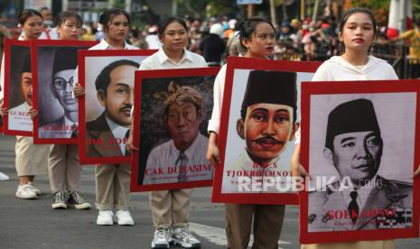 Peserta membawa foto-foto Pahlawan Nasional saat Parade Surabaya Juang di Surabaya, Jawa Timur, Ahad (6/11/2022). Parade Surabaya Juang dalam rangka memperingati Hari Pahlawan itu digelar kembali setelah dua tahun ditiadakan karena pandemi COVID-19. Pimpin Doa di Peringatan Hari Pahlawan, Wamenag: Eratkan Kami dalam Persatuan