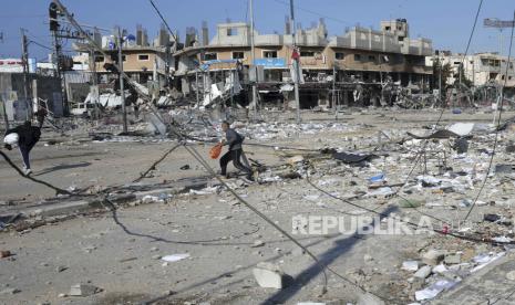 Warga Palestina berjalan melalui kehancuran akibat pemboman Israel di kamp pengungsi Nuseirat di Jalur Gaza, Selasa, 16 Januari 2024.