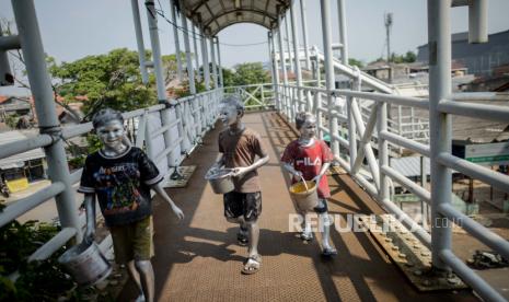 Covid-19 dan Pembayaran Utang Pengasuhan. Anak menggunakan cat di tubuhnya mengamen di Jembatan Penyeberangan Orang (JPO) kawasan Pasar Gembrong, Jakarta, Senin (29/6). Perlunya pengawasan orang tua terhadap anak pasca penerapan pembatasan sosial berskala besar atau era normal baru sebagai upaya mengantisipasi maraknya fenomena manusia silver di Jakarta.