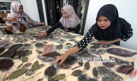 Pekerja membuka daun pada kain yang sudah melewati proses kukus di rumah produsen kain ecoprint Usaha Mikro Kecil Menengah (UMKM) Ija Lhee Sagoe (ILS) di Desa Kuta Blang, Lhokseumawe, Aceh, Senin (9/1/2023). Pemerintah melalui Kementerian Koperasi dan UKM (Kemenkop UKM) terus mendorong pelaku UMKM agar bisa naik kelas, salah satunya dengan bertransformasi dari usaha informal menjadi formal dan memiliki nomor induk berusaha atau NIB. 