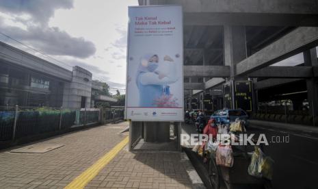 Pedagang sayur melintas di dekat baliho sosialisasi manfaat vaksinasi Covid-19 di kawasan Fatmawati, Jakarta, Selasa (15/12). Badan Pengawasan Obat dan Makanan (BPOM) memperpanjang pengawasan terhadap efikasi maupun efek samping vaksin Covid-19 yang memungkinkan pengumuman keberhasilan atau tidaknya uji klinis tahap tiga vaksin Covid-19 itu terhadap relawan akan ikut mundur ke Maret 2021. Republika/Putra M. Akbar