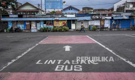 Warga berjalan di area parkiran bus yang kosong di Terminal Cicaheum, Kota Bandung, Jumat (7/5). Selama masa larangan mudik Lebaran pada 6-17 Mei 2021, pelayanan perjalanan bus Antar Kota Antar Provinsi (AKAP) dan Antar Kota Dalam Provinsi (AKDP) di Terminal Cicaheum tidak beroperasi namun angkutan kota, Trans Metro Bandung dan Damri diizinkan beroperasi di wilayah aglomerasi Bandung Raya. Foto: Republika/Abdan Syakura