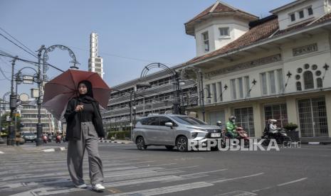 Warga menggunakan payung saat melintasi Jalan Asia Afrika, Kota Bandung, Jawa Barat. Tahun lalu tercatat memiliki rata-rata suhu terpanas sepanjang sejarah.