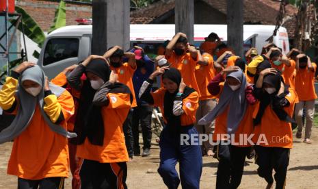 Peserta keluar gedung sambil melindungi kepalanya saat simulasi penanganan bencana gempa di Susukan Rogojampi, Banyuwangi, Jawa Timur, Ahad (7/11/2021). Kegiatan pelatihan oleh Satuan Pendidikan Aman Bencana (SPAB) yang melibatkan 100 orang peserta dari guru dan murid itu sebagai upaya mengurangi resiko jika terjadi bencana di sekolah. 