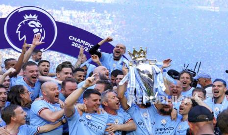 Pemain dan official Manchester City termasuk Pep Guardiola (atas) merayakan dengan trofi Liga Primer setelah kemenangan gelar Liga Primer Inggris pada akhir pertandingan sepak bola Liga Primer Inggris antara Manchester City dan Chelsea di Stadion Etihad di Manchester, Inggris, Ahad, (21/5/2023). 