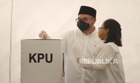 Calon Bupati Kediri Haninditho Himawan Pramono (kiri) didampingi istrinya Eriani Annisa (kanan) menggunakan hak pilihnya pada Pilkada Kabupaten Kediri di Kediri, Jawa Timur, Rabu (9/12/2020). Haninditho Himawan Pramono yang merupakan anak Sekretaris Kabinet Pramono Anung tersebut maju sebagai calon tunggal Pilkada Kediri. 