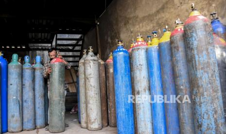 Pekerja memindahkan tabung kosong di agen isi ulang oksigen