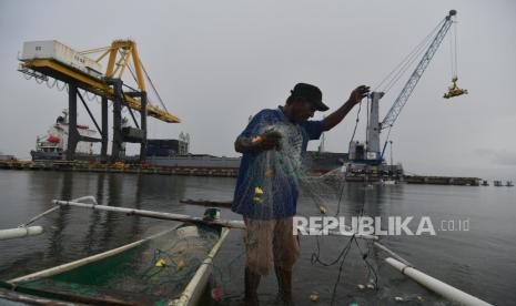 Seorang nelayan menyiapkan jaring untuk melaut dengan latar belakang aktivitas bongkar muat peti kemas di Pelabuhan Pantoloan di Palu, Sulawesi Tengah, Kamis (9/9). Kementerian Koordinator Perekonomian menyatakan akan fokus pada upaya efisiensi sistem logistik nasional khusus untuk produk bahan pangan dan kesehatan.