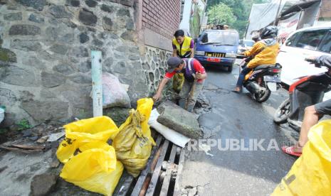 (ILUSTRASI) Petugas membersihkan drainase atau saluran air.