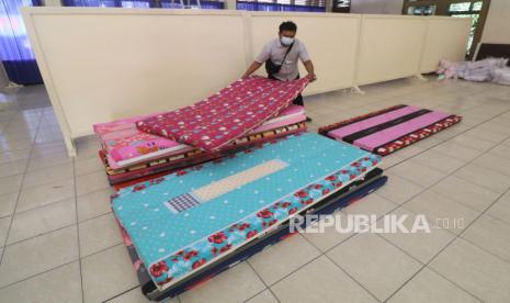 Pekerja menata tempat tidur saat pembangunan ruang isolasi mandiri terpusat.