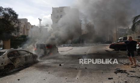 A resident douses burning vehicles in the Israeli city of Ashkelon following rocket launches from Gaza, 07 October 2023. Rocket barrages were launched from the Gaza Strip early Saturday in a surprise attack claimed by the Islamist movement Hamas.  