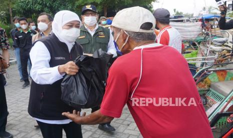 Gubernur Jawa Timur Khofifah Indar Parawansa (kiri) didampingi Bupati Tulungagung Maryoto Birowo (tengah) menyerahkan bantuan sembako kepada pengayuh becak di sela kegiatannya meninjau pelaksanaan vaksinasi COVID-19 yang digelar Ikatan Sarjana Nahdlatu Ulama (ISNU) di Universitas Islam Negeri Sayyid Ali Rahmatullah Tulungagung (UIN SATU), Tulungagung, Jawa Timur, Sabtu (18/9/2021). Gubernur berharap keterlibatan kampus/perguruan tinggi serta multipihak lain dalam penyelenggaraan vaksinasi  OVID-19 akan mempercepat terbentuknya kekebalan komunal atau 