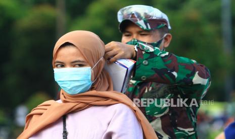 Seorang personel TNI AD memasangkan masker kepada warga yang terjaring razia kepatuhan penggunaan masker di Taman Digulis, Pontianak, Kalimantan Barat, Ahad (12/7/2020). Dinas Kesehatan Kalbar bersama TNI dan Satpol PP gencar melakukan sosialisasi protokol kesehatan dan tes usap atau swab test kepada warga yang terjaring razia kepatuhan penggunaan masker guna mempertahankan zero kasus positif COVID-19 di Kota Pontianak. 