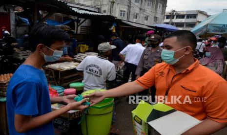 Personel Satgas BUMN Lampung membagikan masker kepada warga di Pasar Pasir Gintung dan Bambu Kuning Bandar Lampung, Lampung, Selasa (29/12/2020). Pembagian masker tersebut dalam rangka sosialisai penerapan protokol kesehatan untuk masyarakat dan pedagang pasar tersebut guna menekan penyebaran COVID-19. 