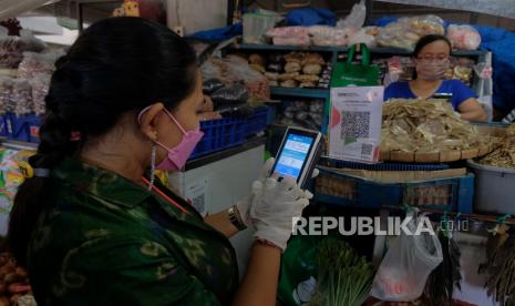 Petugas melakukan penagihan pembayaran retribusi  menggunakan fitur scan QRIS  di Pasar Badung, Denpasar, Bali, Selasa (29/6/2021). Bank Indonesia bersama Bank Pembangunan Daerah (BPD) Bali dan Perumda Pasar Sewakadarma Kota Denpasar bekerjasama dalam menerapkan transformasi digital di tiga pasar tradisional yakni Pasar Badung, Pasar Sanglah dan Pasar Kreneng itu untuk mengantisipasi peredaran uang palsu serta mengurangi kontak fisik antara pedagang dan konsumen sebagai upaya pencegahan penyebaran COVID-19. 