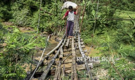 Warga melintasi jembatan gantung bambu yang rusak di Desa Kertamukti, Kecamatan Cipatat, Kabupaten Bandung Barat, Rabu (24/6). Jembatan gantung penghubung Desa Kertamukti dan Desa Cipatat tersebut sudah rusak dan lapuk sehingga dapat membahayakan warga yang melintas. Foto: Abdan Syakura/Republika