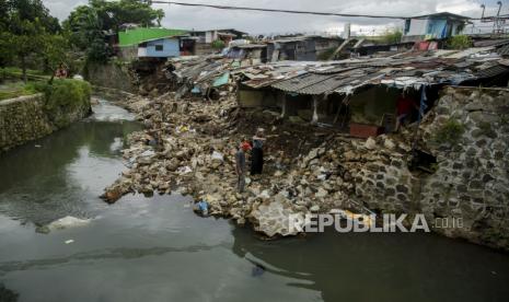 Warga melihat kondisi rumah dan tembok bantaran sungai yang roboh pascabanjir di kawasan Sirnaraga, Bandung, Jawa Barat, Jumat (25/12/2020). Puluhan rumah dan kirmir di sepanjang bantaran Sungai Citepus Kota Bandung roboh dan ambruk akibat banjir luapan yang terjadi pada Kamis (24/12/2020) lalu.