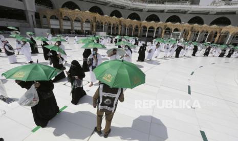 Seorang polisi Saudi, tengah, mengawasi peziarah saat mengelilingi Ka