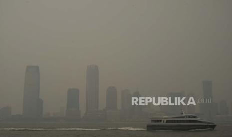 Bangunan di Jersey City sebagian tertutup kabut asap dari kebakaran hutan Kanada saat kapal feri melintasi Sungai Hudson, terlihat dari wilayah Manhattan di New York Rabu, (7/6/2023). 