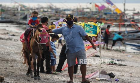 Warga menggunakan jasa menunggang kuda di kawasan Pantai Kenjeran, Surabaya, Jawa Timur, Ahad (21/6/2020). Pakar epidemiologi dari Fakultas Kesehatan Masyarakat (FKM) Universitas Airlangga (Unair) Laura Navika Yamani menilai ada beberapa penyebab tingginya kasus virus corona SARS-CoV2 (Covid-19) di Jawa Timur (Jatim) dan menyaingi Jakarta dalam beberapa hari terakhir. Di antaranya banyaknya spesimen yang dites hingga masyarakat yang masih abai dengan protokol kesehatan.