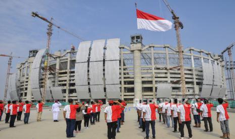 Sejumlah pekerja PT Jakarta Propertindo (Jakpro) dan Kerja sama Operasional (KSO) mengikuti upacara HUT Kemerdekaan ke-76 Republik Indonesia di proyek pembangunan Jakarta International Stadium (JIS), Tanjung Priok, Jakarta Utara, Selasa (17/8/2021). Dalam rangka peringatan HUT Kemerdekaan ke-76 Republik Indonesia, JakPro mengadakan upacara sekaligus pengibaran bendera merah putih berukuran 17 x 8 meter dengan menggunakan alat berat 