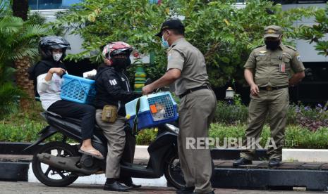 Petugas Satpol membantu warga pemilik hewan saat kegiatan vaksinasi rabies drive thru gratis di halaman Kantor Wali Kota Jakarta Timur, Selasa (28/9/2021). Kegiatan yang diselenggarakan Sudin Ketahanan Pangan, Kelautan, dan Pertanian (KPKP) Jakarta Timur  dalam rangka Hari Rabies Sedunia dalam upaya memberikan pelayanan kepada masyarakat yang memiliki hewan peliharaan agar terjamin kesehatannya bebas dari penyakit rabies dengan target  200 hewan selama dua hari pelaksanaan sejak 27-28 September 2021. 