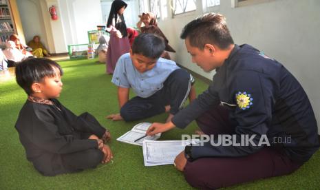 Dai dan remaja masjid membimbing anak-anak membaca Alquran.